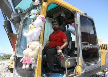 Kaldırdığı enkazlardan çıkan oyuncakları kepçesine asıp çalışıyor