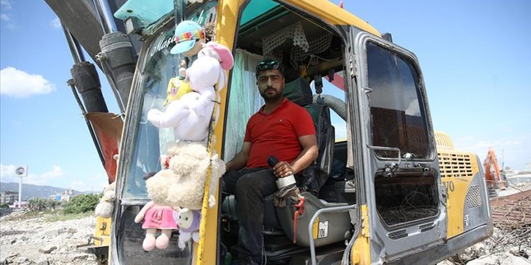 Kaldırdığı enkazlardan çıkan oyuncakları kepçesine asıp çalışıyor